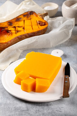 Pumpkin marmalade. Homemade pumpkin jelly candies on white plate on gray background.