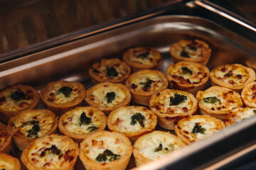 Beautifully decorated banquet catering table, with variety of with different food snacks appetizers on corporate birthday party event or wedding celebration, canape, salad, delicatessen setting