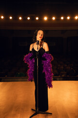 Woman singing on stage in vintage style with a retro microphone and dramatic lighting