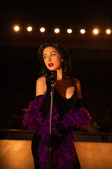 Woman singing on stage in vintage style with a retro microphone and dramatic lighting