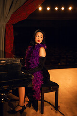 Piano performance by a singer in glamorous attire on stage during an evening event