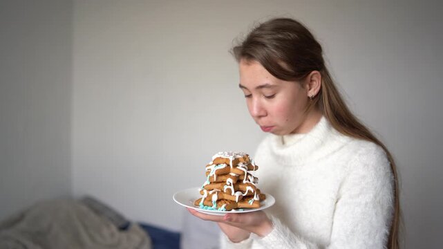  teenage girl bites into a gingerbread Christmas tree