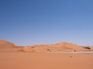 Desert landscape of the Red Tadrart with rock formations and golden sand under a blue sky. Natural scenery of the Algerian Sahara.