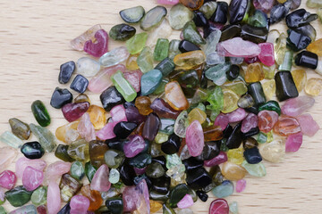 Tourmaline heap up jewel stones texture on light varnished wood background
