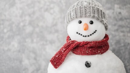 Whimsical and charming snowman figure adorned in a warm red scarf and grey knit hat standing in a serene and frosty winter wonderland landscape covered in pristine white snow