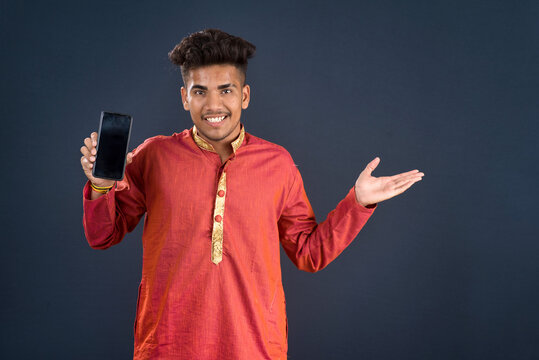 Young handsome traditional man showing a blank screen of a smartphone or mobile phone