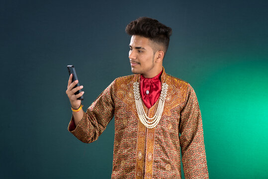 Young handsome man holding and using smartphone or mobile phone