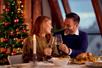 Couple Toasts With Wine Glasses During Cozy Christmas Dinner By Tree and Candlelight