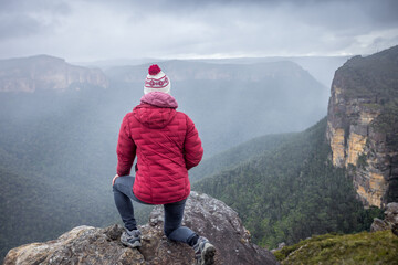 Female hiker at mountain peak clifftop overlooking misty valley