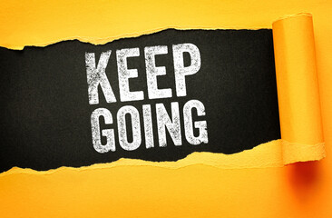 Keep Going motivational text in bold distressed font on a torn paper background. The ripped yellow sheet reveals a black backdrop, symbolizing persistence, resilience, and determination