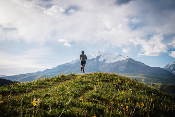 Trail runner running on the high altitude grassland mountain top trail