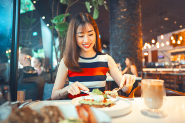 Beautiful smile asian woman healthy eating breakfast menu at restaurant sitting near window indoors on day