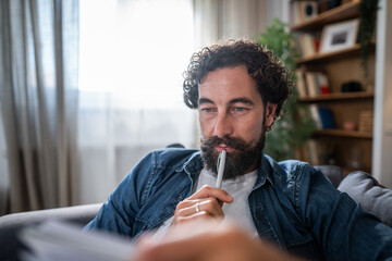 Thoughtful man writing in journal at home