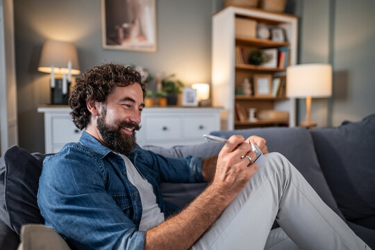 Smiling man relaxing on couch writing notes