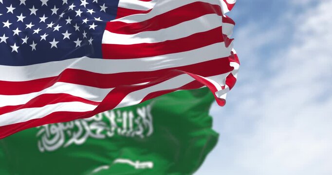 Saudi Arabian and American flags waving together in sky,