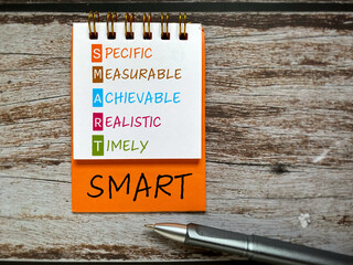 SMART - specific, measurable, achievable, realistic, timely note written on notebook with copy...
