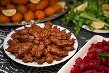 Plate of traditional cig kofte served with beet salad, greens and lemon slices. Traditional middle eastern and turkish cuisine kibbeh. Spicy bulgur raw meatballs. Table dinner concept