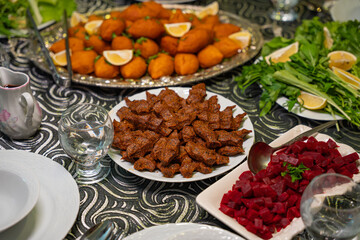 Plate of traditional cig kofte served with beet salad, greens and lemon slices. Traditional middle eastern and turkish cuisine kibbeh. Spicy bulgur raw meatballs. Table dinner concept