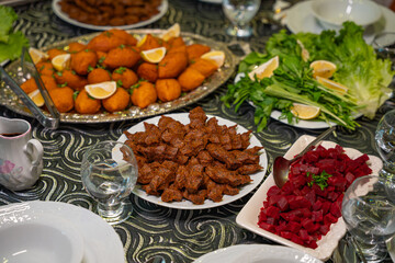 Plate of traditional cig kofte served with beet salad, greens and lemon slices. Traditional middle eastern and turkish cuisine kibbeh. Spicy bulgur raw meatballs. Table dinner concept
