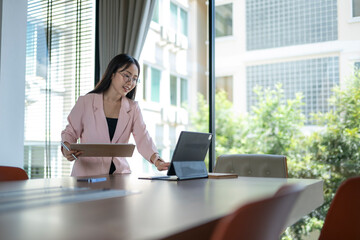 Businesswoman using tablet and holding documents in meeting room