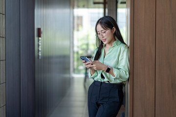 Businesswoman using smartphone in modern office corridor
