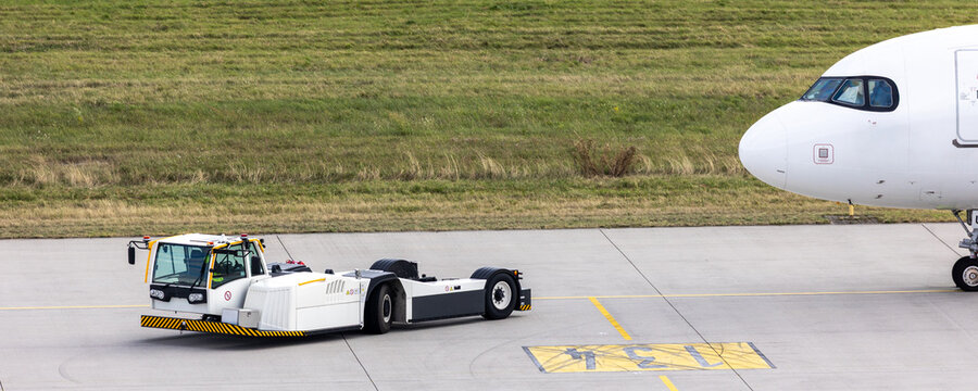 Fototapeta Modern regional jet aircraft towed by ground vehicle on airport taxiway tarmac under sunlight. Engine cockpit clearly visible crew performs technical operations before next scheduled flight airport