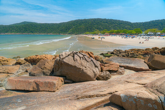 Guaiuba Beach, Guaruja SP, Brazil. Sunny day over the small bay with tranquil sea. Image of leisure and tourism on the Sao Paulo coast. Hills covered in Mata Atlantica vegetation frame the view.