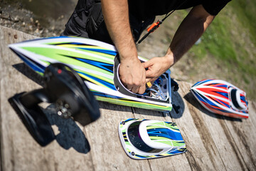 Technician repairing radio controlled toy boat on wooden dock