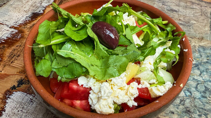 Rustic terracotta bowl brimming with Mediterranean salad, feta crumbles, arugula, evoking sun-drenched Greek Easter or Olive Festival