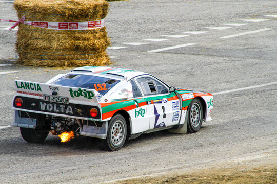 San Marino: 2010 09 01 Rally free eventDramatic rear view of a white, green, and red liveried Lancia Rally 037 racing car with flames shooting from the exhaust pipe during a histori