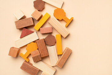 Wooden children's construction set blocks of different shapes natural colors on beige background. Montessori style cubes game for toddlers flat lay top view. Concept of learning and education