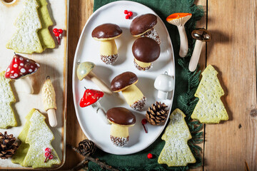 Mushroom and fir-shaped cookies made from shortcrust pastry and ceramic mushrooms on a wooden background.