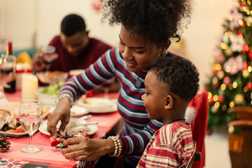 African mother playing toy with her son at the dining table on Christmas festive holiday. Famity gathering for celebrating New year together