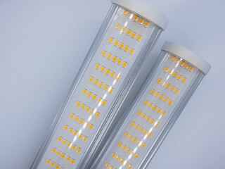Two LED light tubes with yellow diodes on a light gray background