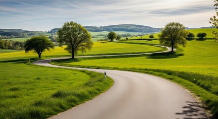 Scenic countryside road winding through lush green rolling hills under a cloudy sky