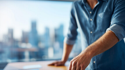 Fototapeta premium torso of a person in smart casual rolling up sleeves at a standing desk city lines defocused beyond cool daylight space on right for message sleeves rolled