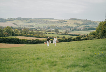 Fototapeta premium Two women are walking in a field with a beautiful view of the mountains in the background