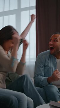 Group fans multiracial four friends watch television celebrating win sport game championship match supporting football team at home party buddies guys girls raising hands in excitement victory indoors