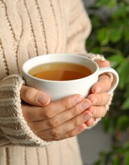 Warm Hands Holding a Mug of Herbal Tea on a Cold Day