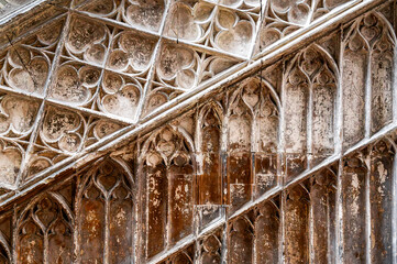 An old stone wall with carved Gothic decorative elements arranged diagonally, partially painted and...