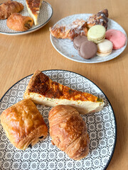 French breakfast table with croissants, quiche slice, colorful macarons on patterned plates