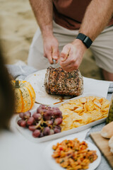 A man is cutting a large piece of meat on a table with a variety of food