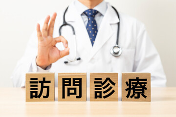 「訪問診療」と書かれたブロックとOKサインをする医師