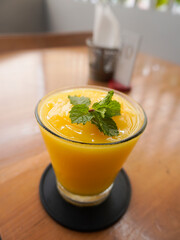 A glass of fresh Mango Peach on wooden table	