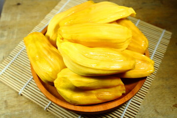 Fresh yellow jackfruit bulbs in a wooden bowl