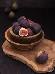 Half Sliced Fig on Wooden Board with Whole Figs and Vase in Background