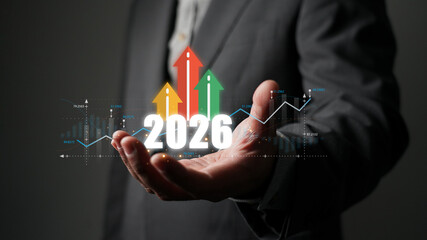 Businessman holding a hologram of 2026 with a growth chart and arrows. Concept of business goals, investment, financial planning, and future success for the new year.