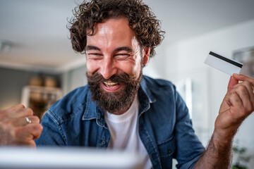 Happy man celebrating online shopping success with credit card