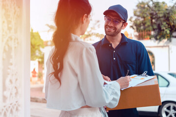 A woman receives a package and scans it to pay the delivery man during rush hour outside her house.	