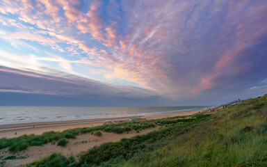 Pastel clouds paint the sky over a serene beach